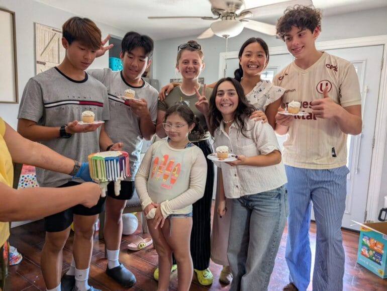 一群朋友在室內圍著生日點心合照