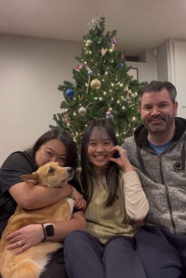 三人與一隻狗坐在聖誕樹前合照