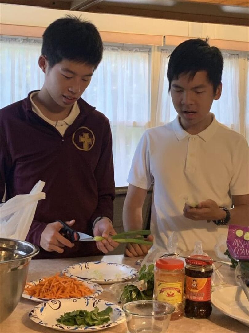兩名少年在擺有蔬菜、醬料和料理食材的流理台前備餐